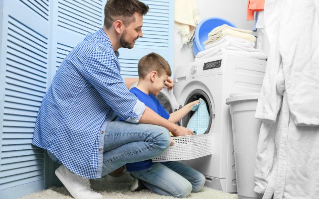 Adult and child loading a washing machine